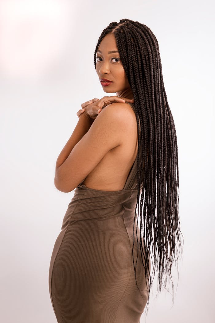 Graceful pose of an African American woman with long braids in a studio setting.